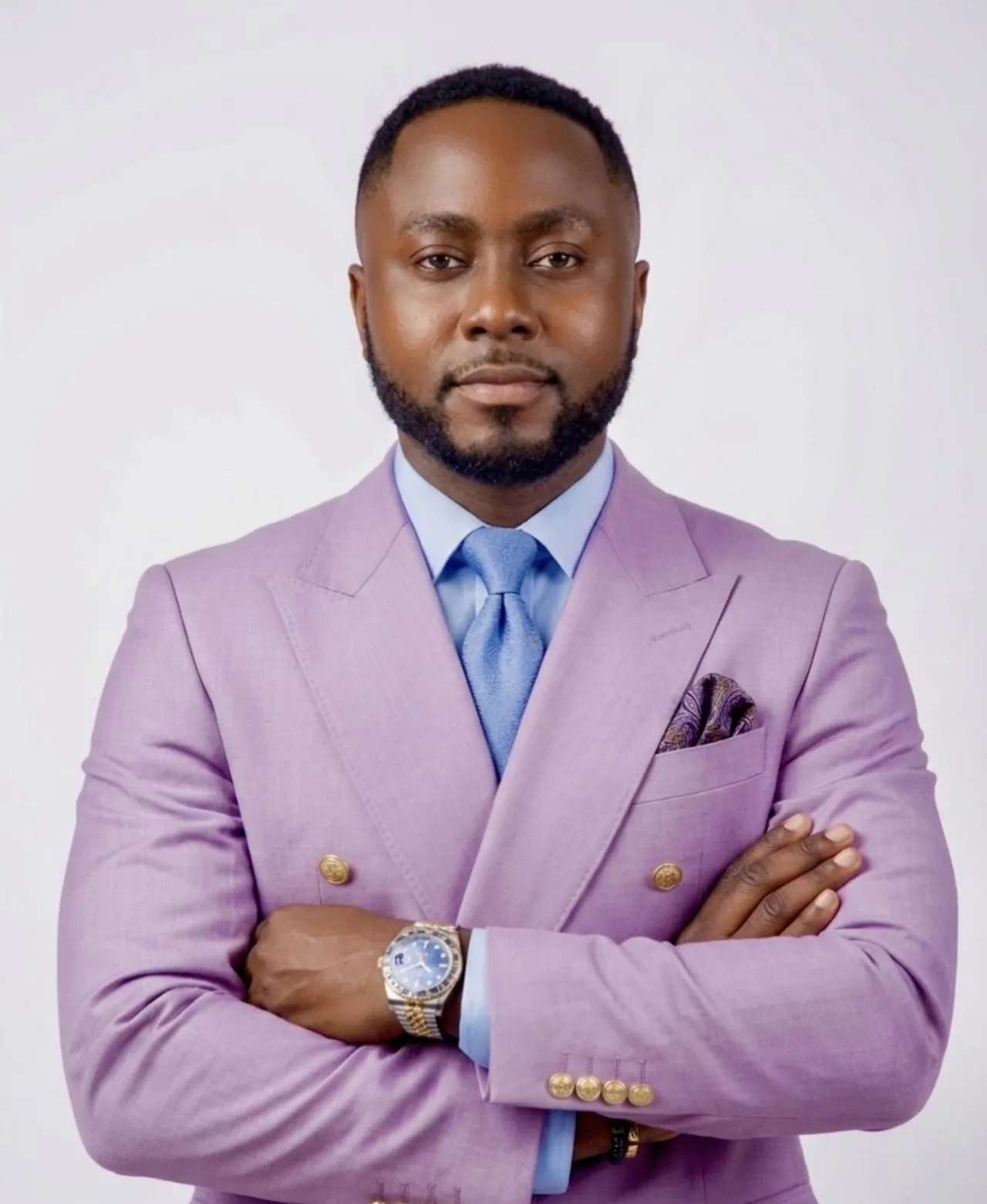 Portrait of Edwin Elikem Amenyeawu in a lilac double-breasted suit, arms folded